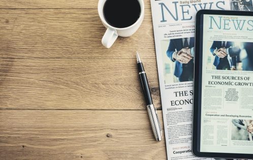 Newspaper and digital tablet on wooden table