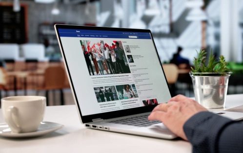 person looking at news on laptop in cafe