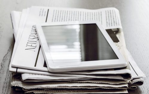 Newspaper and digital tablet on wooden table