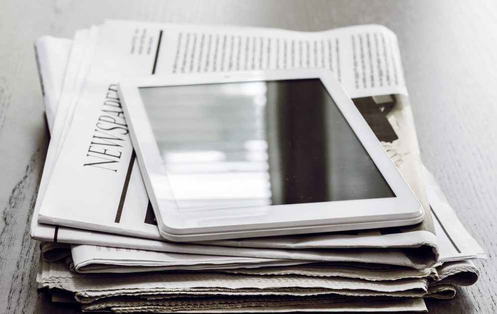 Newspaper and digital tablet on wooden table