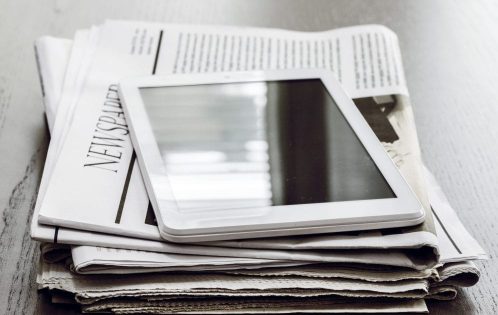 Newspaper and digital tablet on wooden table