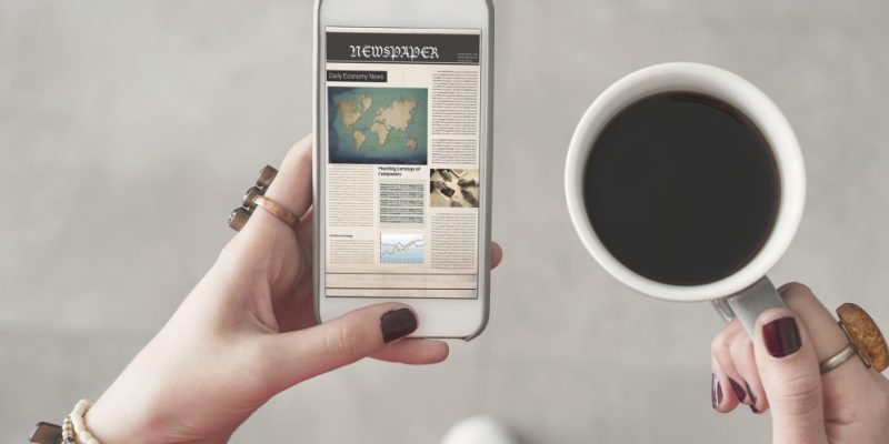 person holding a phone and cup of coffee