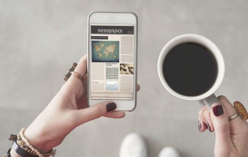 person holding a phone and cup of coffee